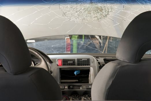 Detail shot of a shattered car windshield in a repair shop. Shot from inside the car.