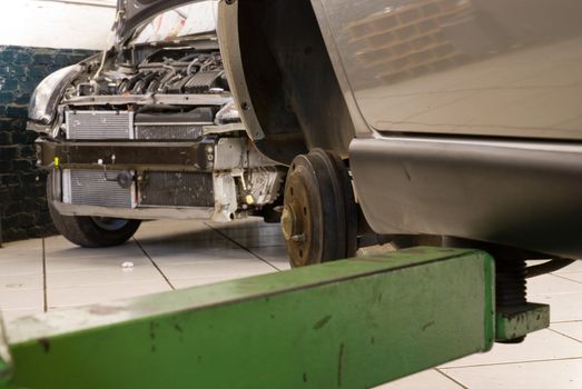 Detail shot of a car without wheels lifted by a repair shop lift