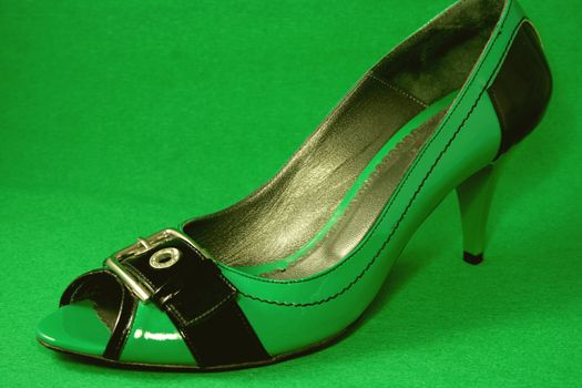 Green High-Heeled Shoes Close-up on green background. Series