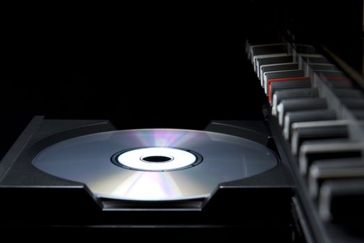 Detail shot of a CD in a player's drawer with crossover buttons on the top right, in perspective. Side shot with dark background.