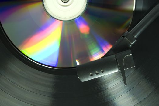 Cropped image shot directly from above of a record player needle, with LP  and CD underneath