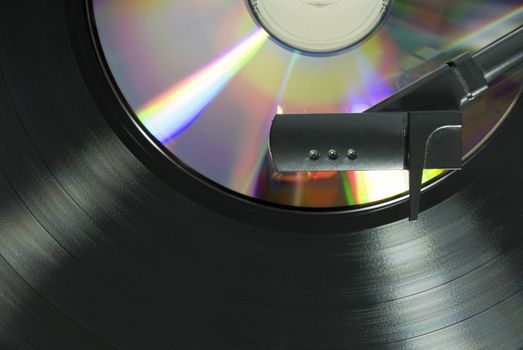 Cropped image shot directly from above of a record player needle, with LP  and CD underneath