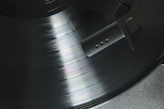 Cropped image shot directly from above of a record player needle, with LP underneath