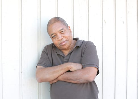 Portrait of an african american man standing against a wall outdoors.