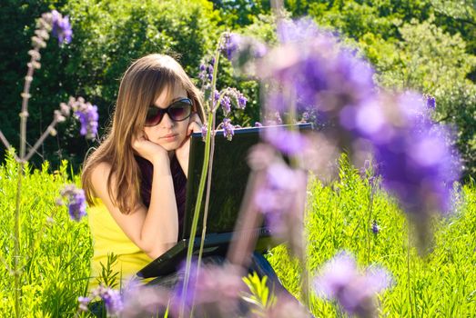 Young beautiful woman with laptop outdoor. Sunny summer day.