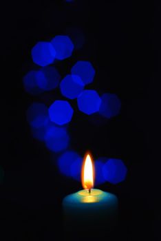 Burning candle on a blurred color background