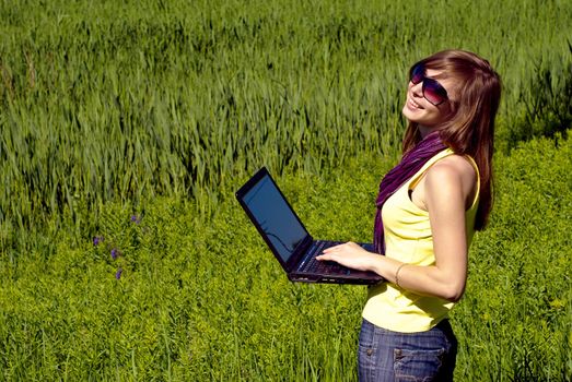 Young beautiful woman with laptop outdoor. Sunny summer day.