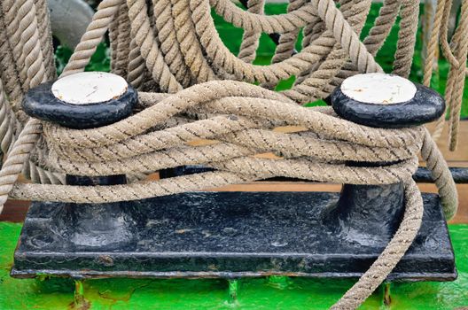 Heavy twisted ropes on the cast iron mooring bollard