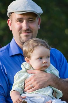 A proud young father holding his baby boy with a smile on his face.