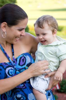 A young mother tickles her baby happily.