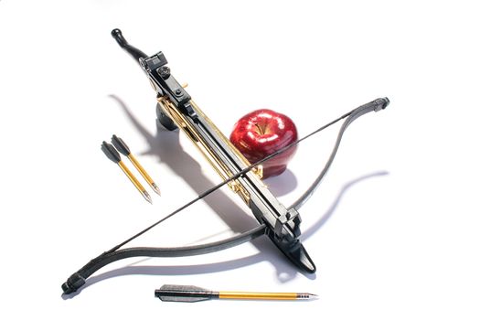 Crossbow with arrows and a red apple.