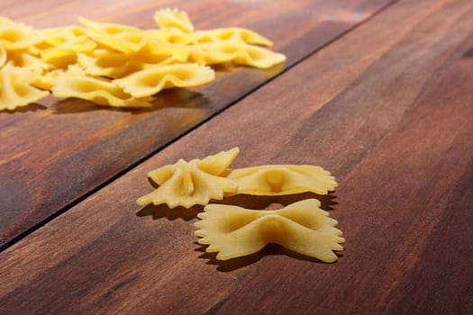 Vermicelli in the form of bows on a wooden kitchen table.