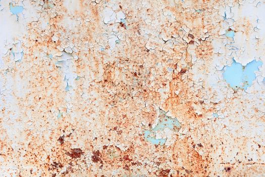 The rusty weathered surface of a steel sheet with paint scraps