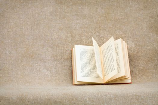The open old book against a rough brown canvas
