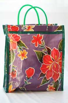 A purple shopping bag with floral pattern and green piping