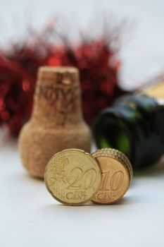 Two euro coins in front of an open champagne bottle and cork