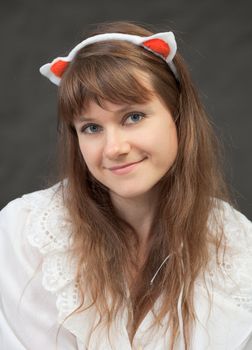 The smiling beautiful girl in a white chemise and with glamour ears