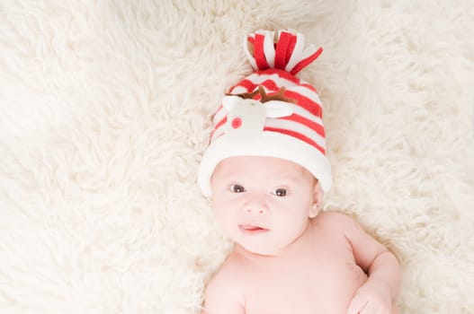 Newborn baby in chritstmas hat lies on fur