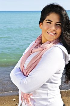 Portrait of beautiful smiling brunette girl at beach with crossed arms