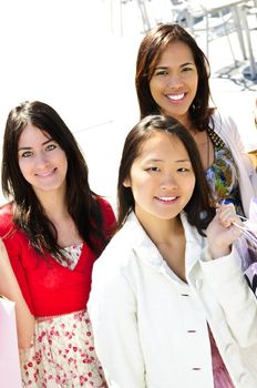 Three young girl friends holding shopping bags at mall