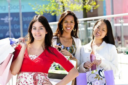 Three young girl friends holding shopping bags at mall