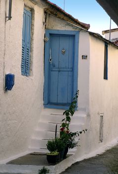Traditional greek white house with blue door and window.