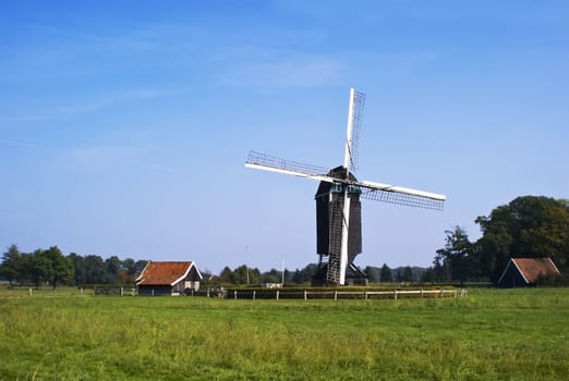 Dutch windmill in rural scene, green grass, blue sky.