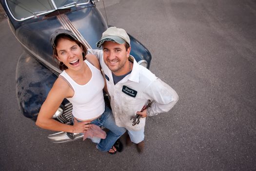 Couple posing with vintage sedan and tools