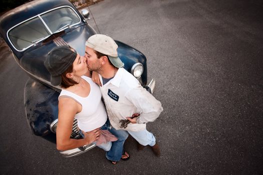 Couple posing with vintage sedan and kissing