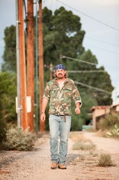 Rugged man in camoflauge walking on dirt road