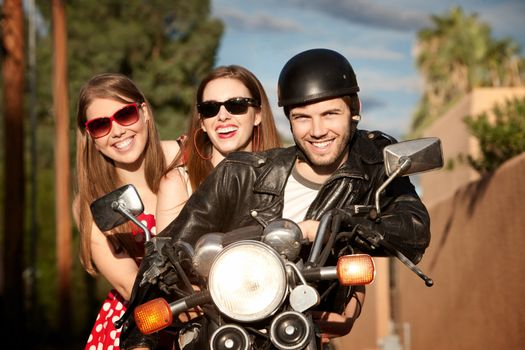 Three young adults posing on vintage motorcycle