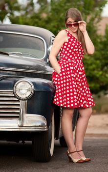 Young girl in red polka dot dress with vinatge car