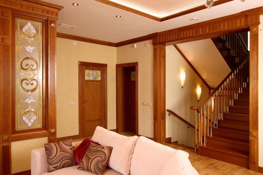 Interior of a modern room with a sofa, stained-glass windows and a ladder on the second floor
