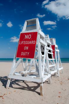 Empty lifeguard tower chair with not on duty sign