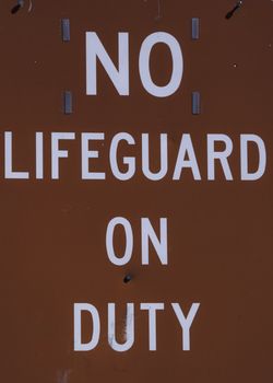 Empty lifeguard tower chair with not on duty sign