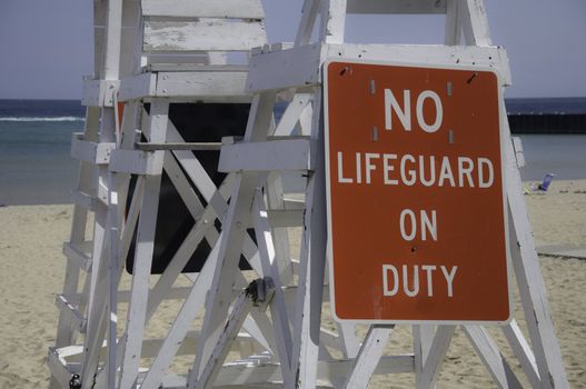 Empty lifeguard tower chair with not on duty sign