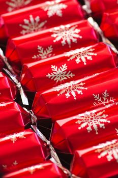 Closeup of many red Christmas crackers in a row