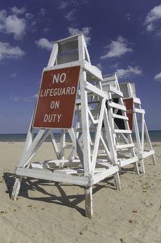 Empty lifeguard tower chair with not on duty sign