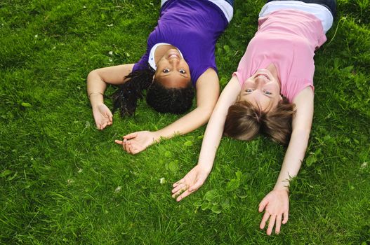 Two teenage girls laying on grass arms outstretched