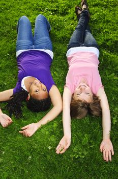 Two teenage girls laying on grass arms outstretched