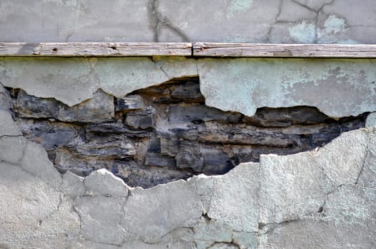 Ancient cracked concrete wall with exposed stones