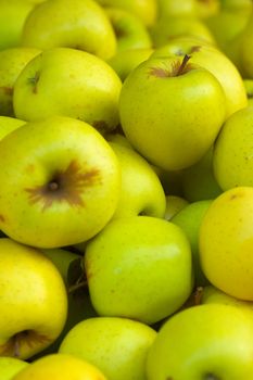 a pile of green golden delicious apples at the market