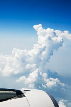 Part of airplane against fluffy clouds