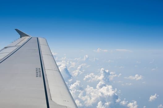 Wing of airplane against fluffy clouds