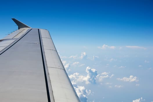 Wing of airplane against fluffy clouds