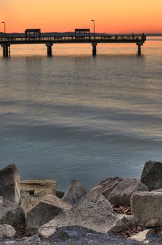 Fishing pier over water in bay with rocks in foreground at Washington waterfront