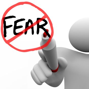 A person draws the word Fear and a red circle and slash over it with a red felt marker on a glass board, illustrating the determination to conquer fears and anxieties