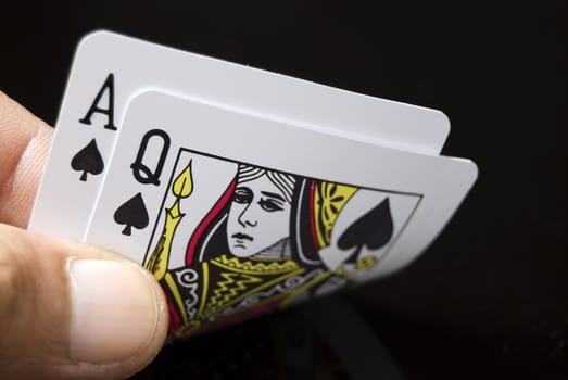 Blackjack cards held by hand against black background