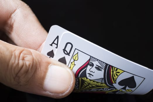 Blackjack cards held by hand against black background