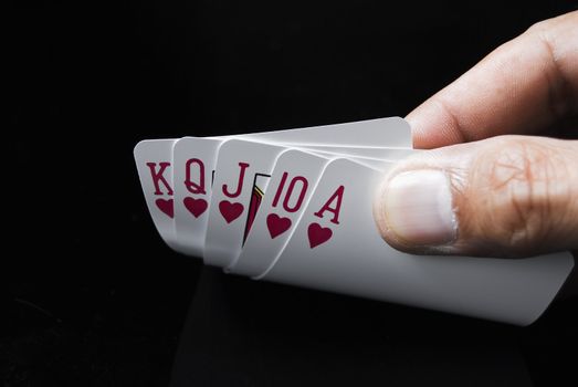 Royal Flush held by hand against black background